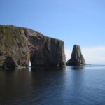 grey cliff on blue calm sea during daytime