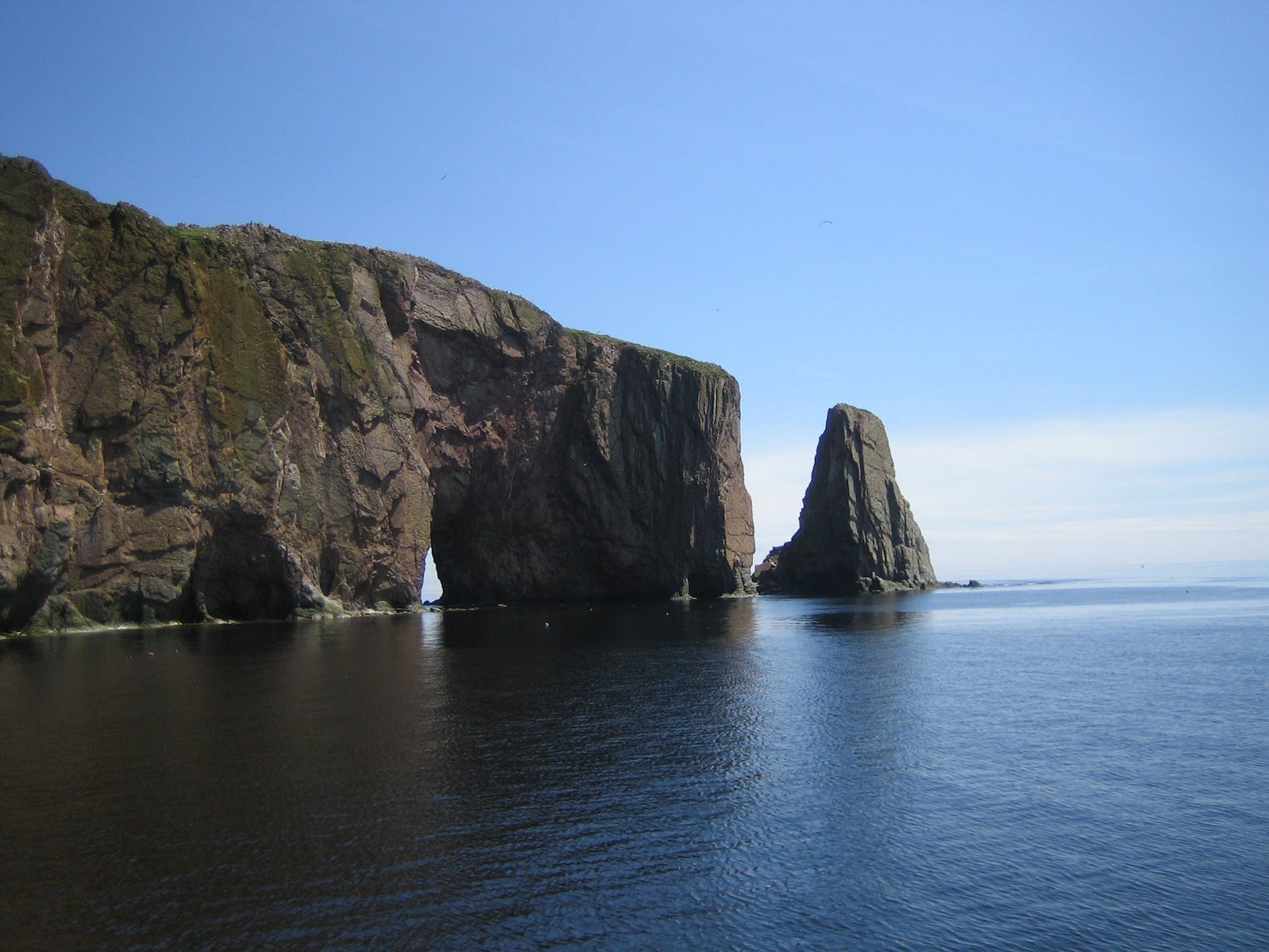 grey cliff on blue calm sea during daytime